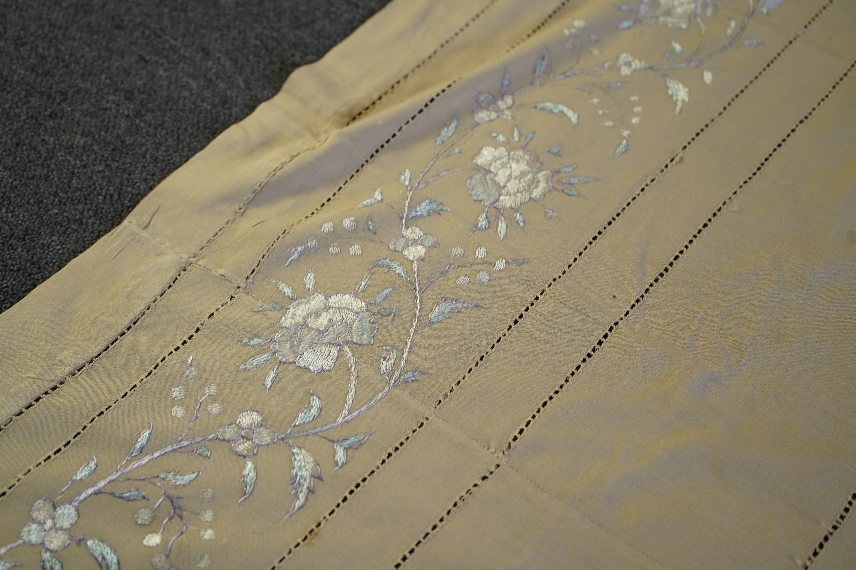 A 1920’s heavy shantung silk hand embroidered table cover. Worked with decorative rows of button hole stitch. Embroidered with white, green and blue silk flowers. 240cm x 204cm. Condition - some fine holes near corners,